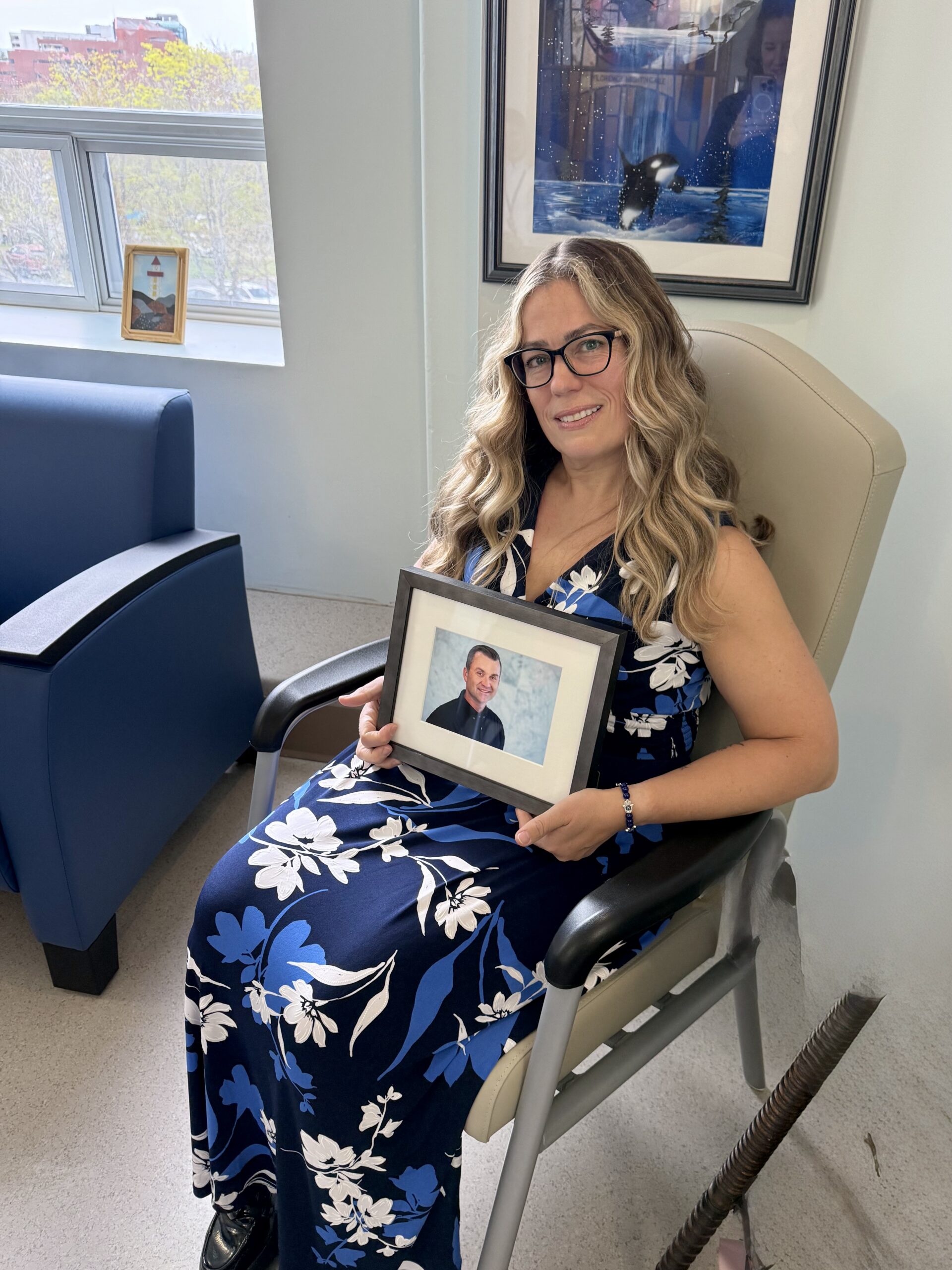 Christine holding a framed photo of Chris in a palliative care family room