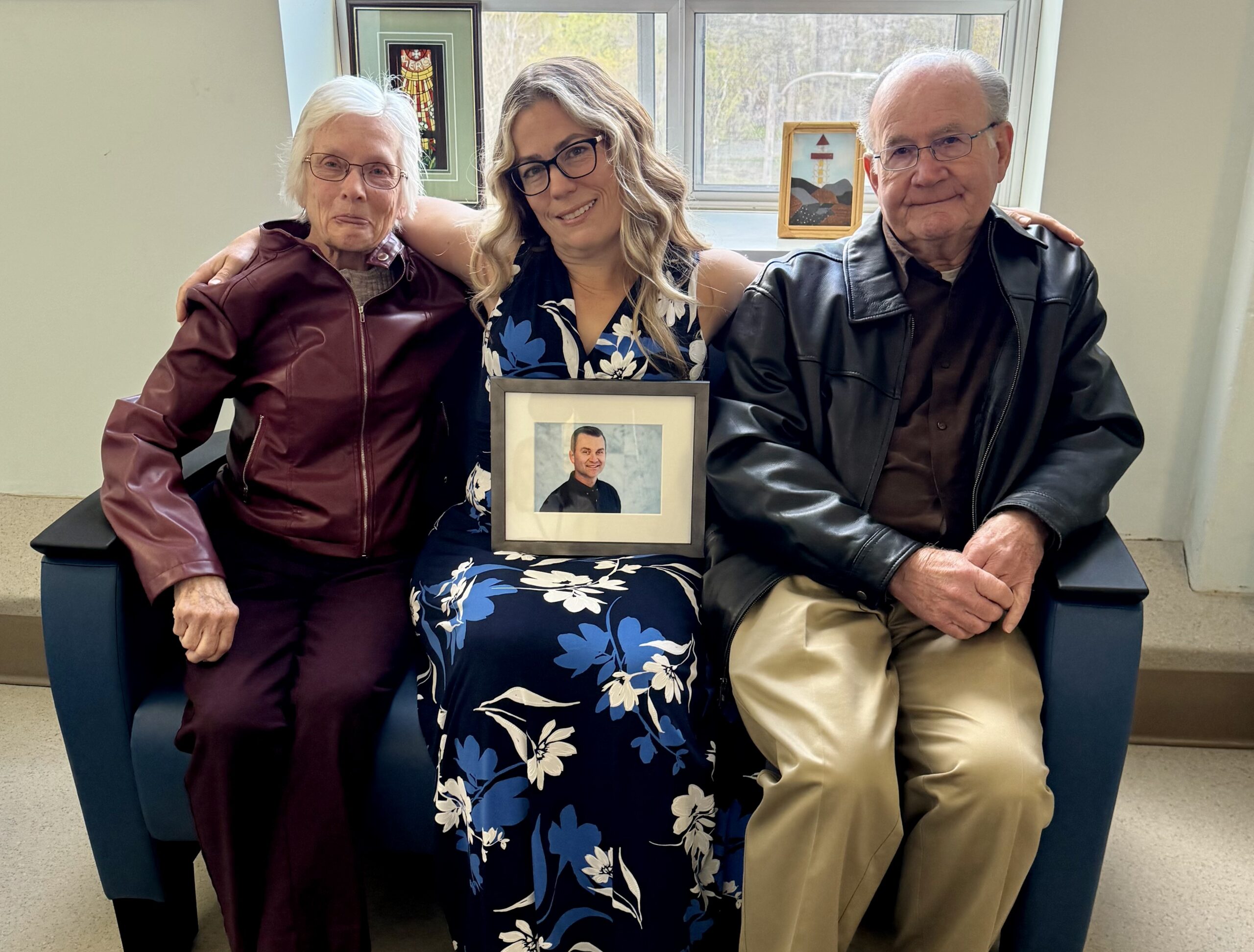 Family seated together holding a framed photo in a palliative care family room