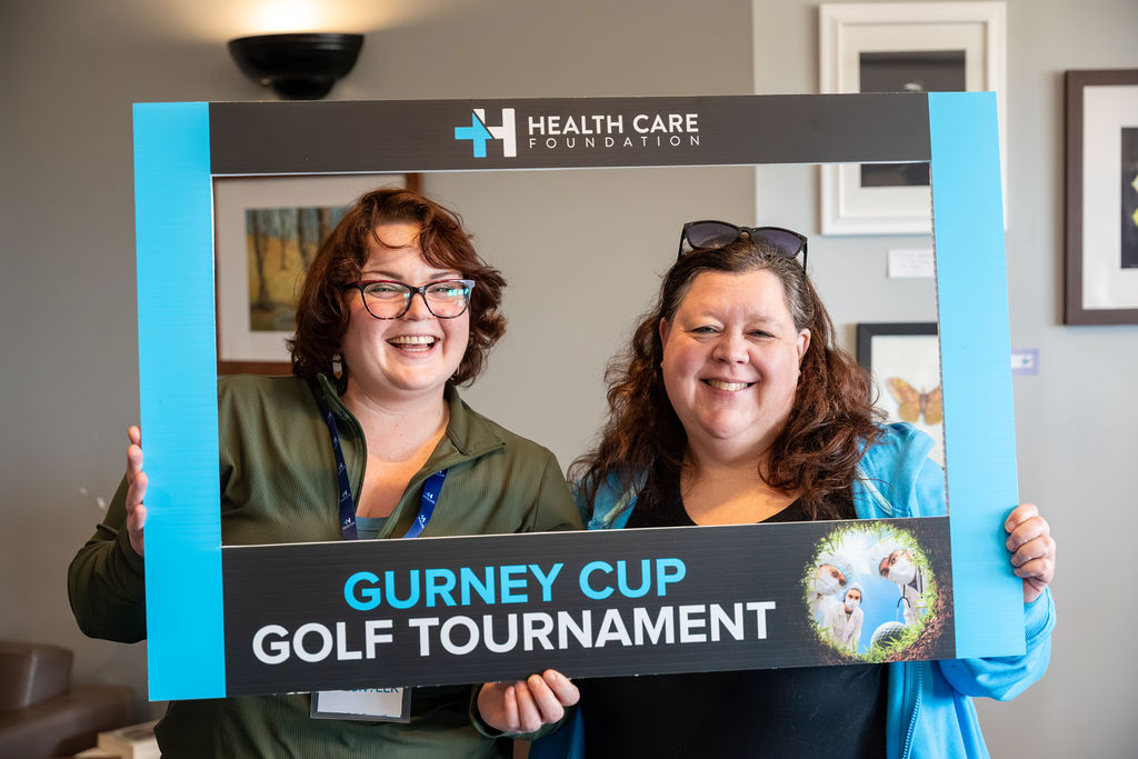 Two participants smiling in a photo frame at the 2026 Gurney Cup Golf Tournament