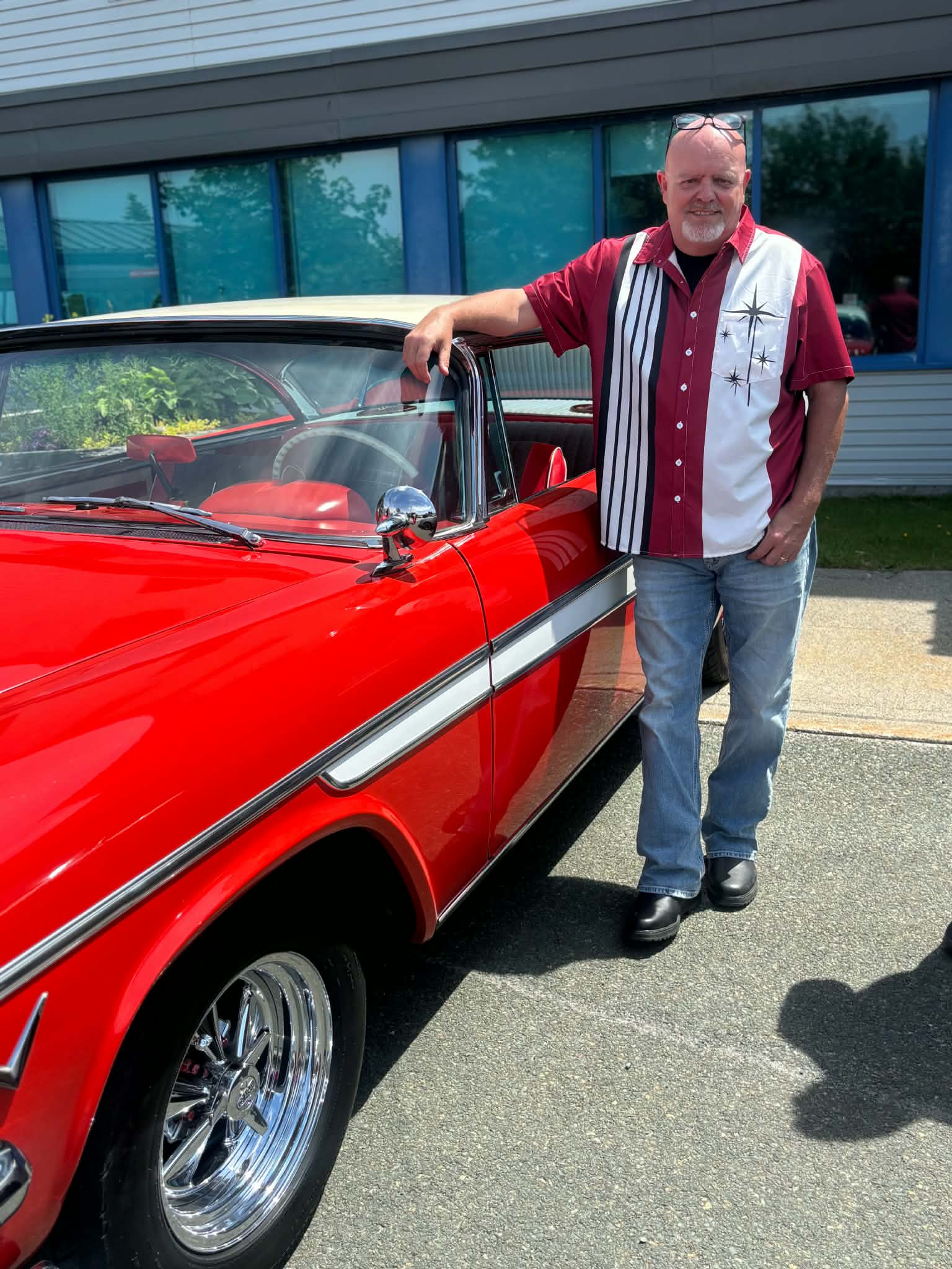 Participant standing beside a red classic convertible at a Health Care Foundation car show