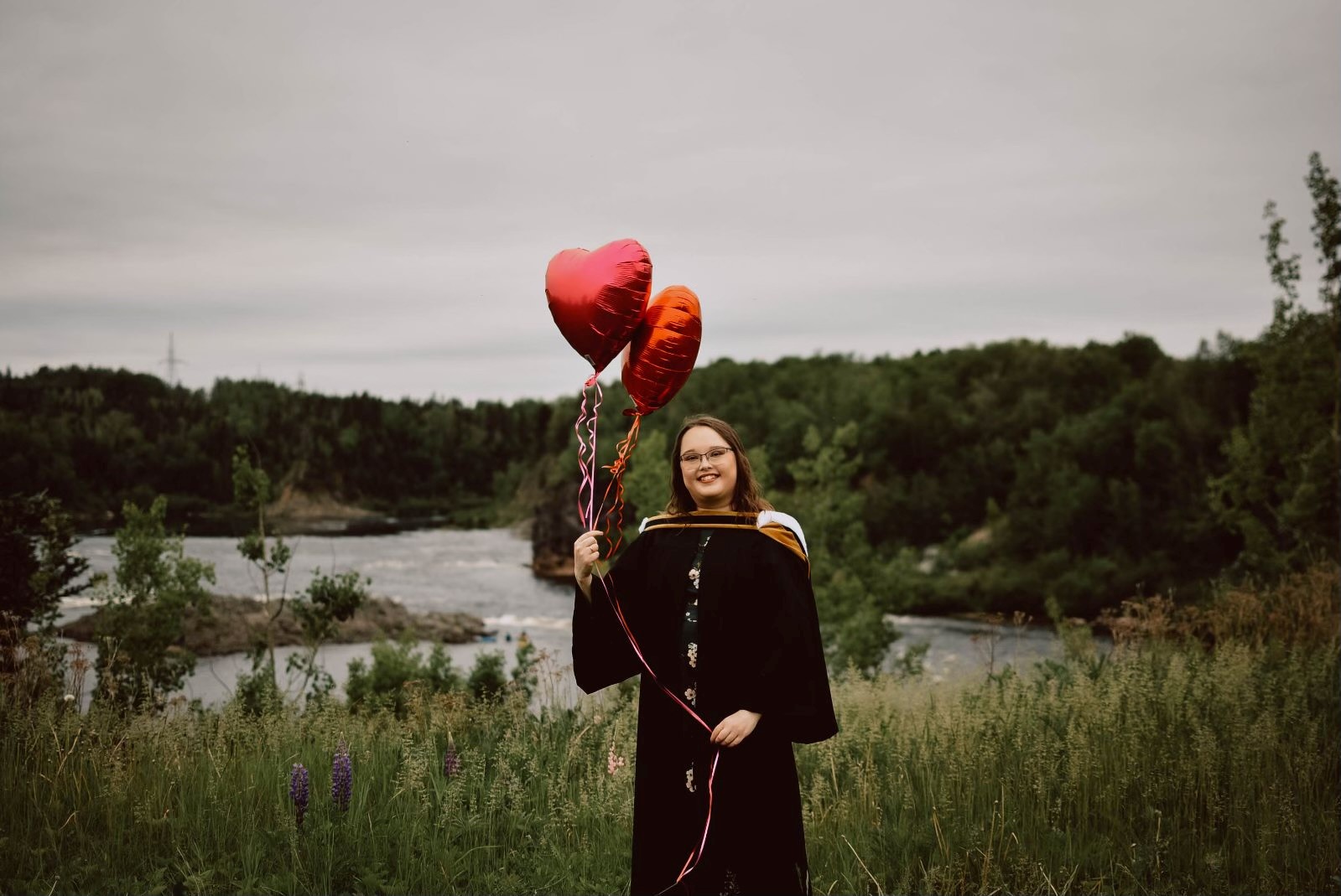 Amanda Saunders standing outdoors holding red balloons