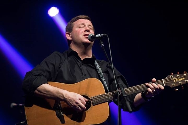 John Curran playing guitar and singing on stage