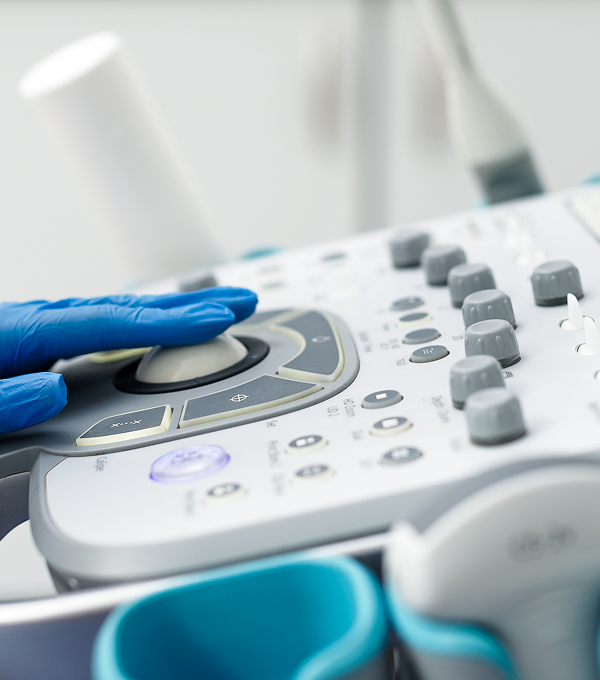 Close-up of a gloved hand adjusting an ultrasound machine control panel