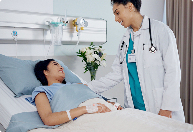 Doctor speaking with a patient resting in a hospital bed