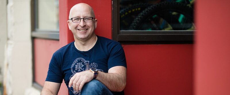 Steve Callahan smiling in front of a red building