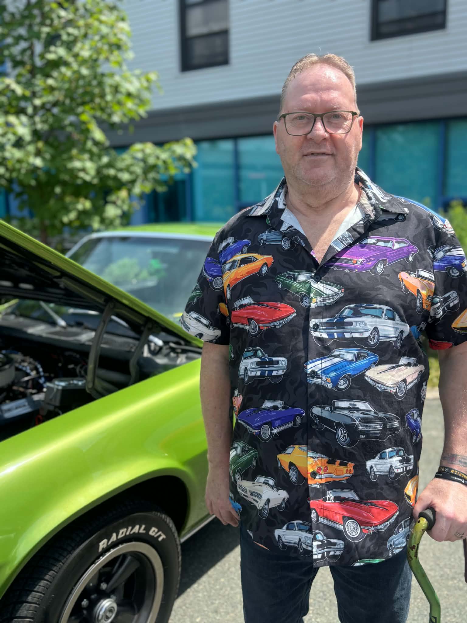 Participant standing beside a green classic car at a Health Care Foundation car show