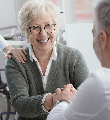 Smiling older woman shaking hands with a visitor