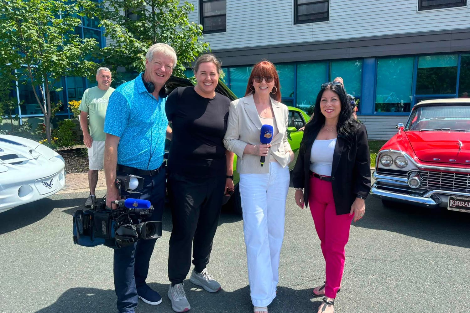 NL Health Services staff matching grant presentation beside classic cars