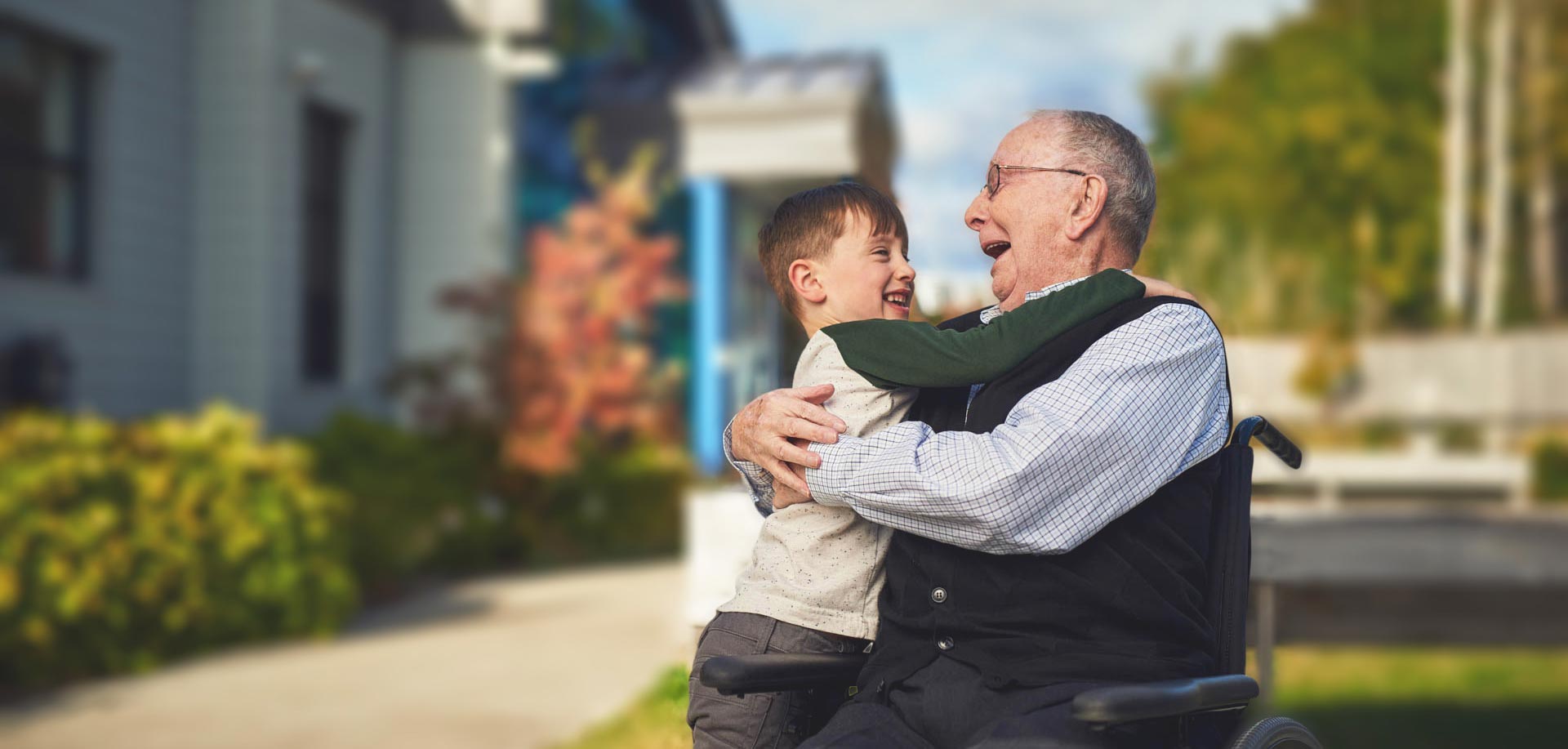 Older man embracing a family member outside a home