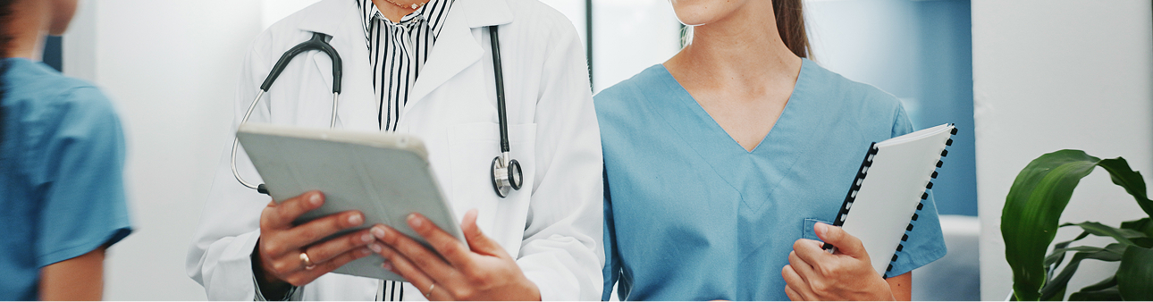 Health care workers in scrubs reviewing a tablet