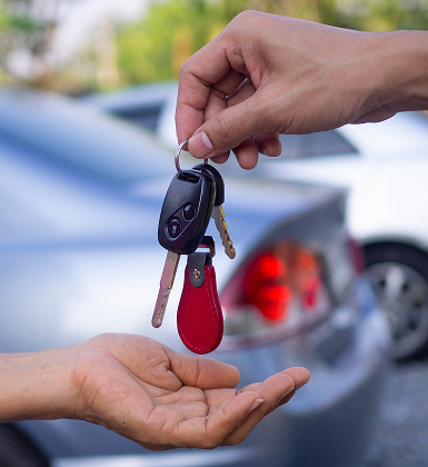 Hand passing car keys to another person